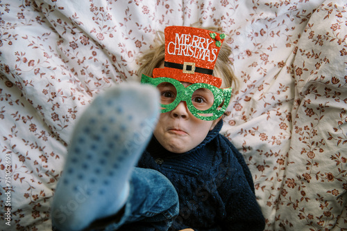 smiling toddler in blue knit sweater with christmas glasses photo