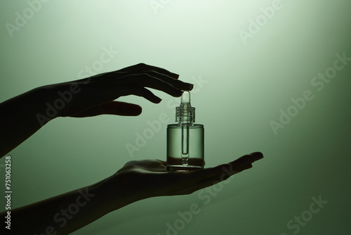 mockup of glass bottle with dropper lid in female hands photo