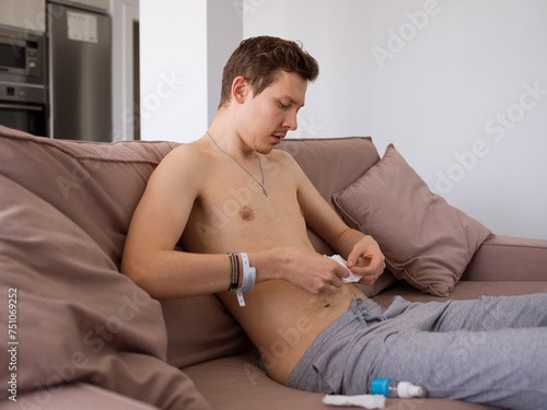 Young man attaching sticky antibacterial patch on belly