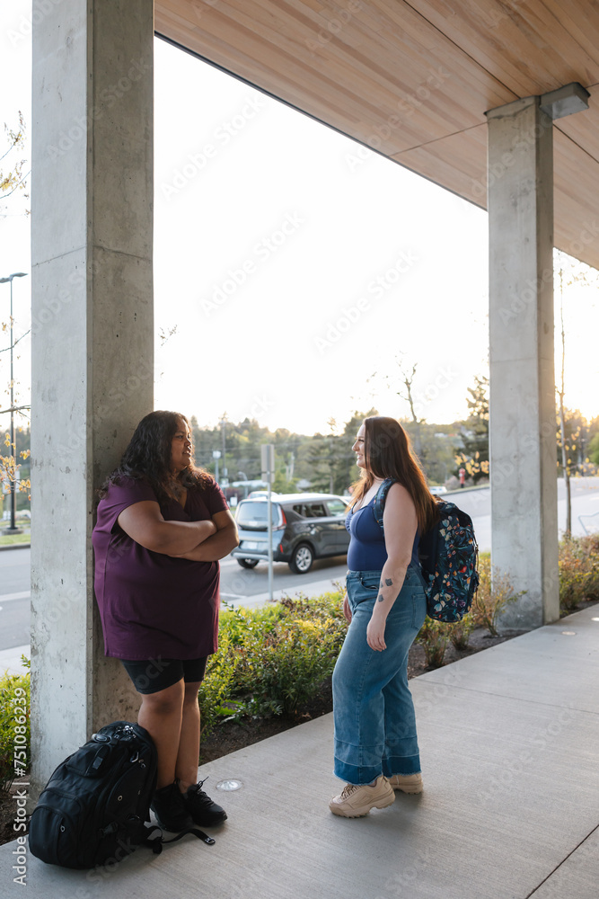 Two women standing near concrete columns talking. Two women standing near concrete columns talking.