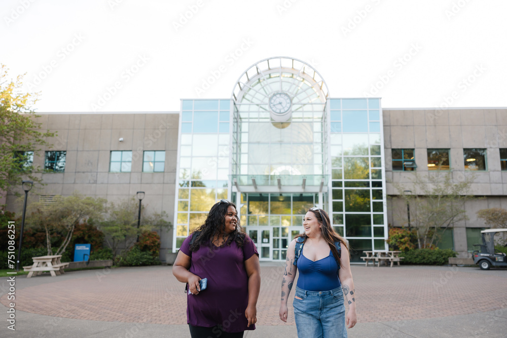 © Rob and Julia Campbell/Stocksy - Two female students walking and talking together on campus.