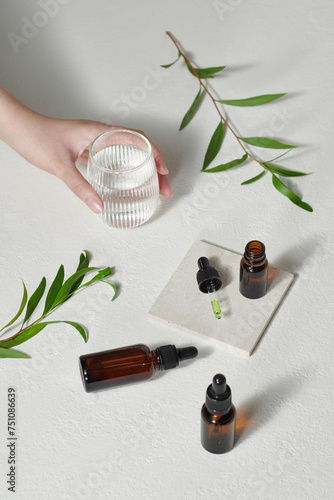 Oil of tea tree systems in small warm bottles on white surface photo