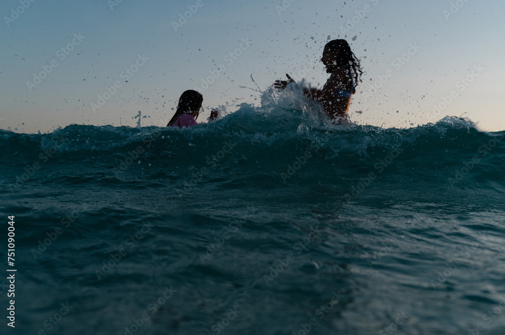 Two kids jumping in the water at blue hour Two kids jumping in the water at blue hour