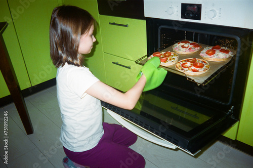 Daughter taking pizza out of the oven. photo