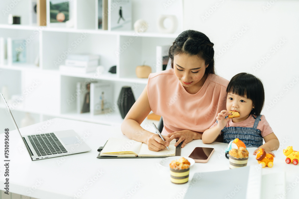 Young asian child writing something in notebook with mother Young asian child writing something in notebook with mother