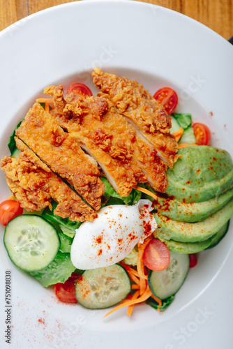 A plate of food with chicken, avocado, and vegetables