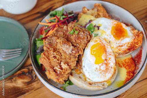 A plate of fried chicken, eggs, and toast is served on a wooden table