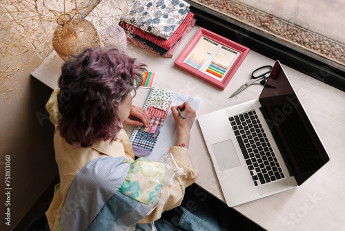 Fashion designer working with laptop and textile samples photo