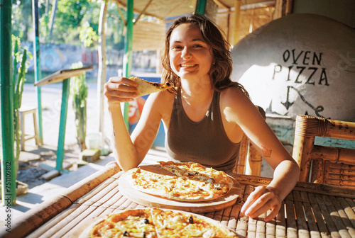 Cheerful woman eating pizza and looking at camera photo