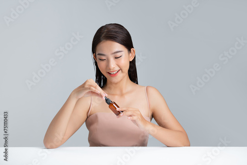 Girl using anti-aging cosmetics for smoother skin tone on gray photo