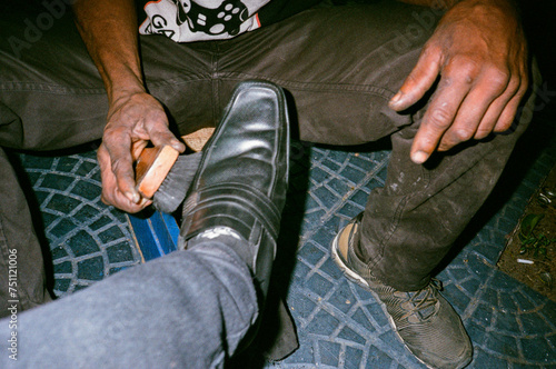 Shoe shiner street worker polishing his client's leather shoes photo
