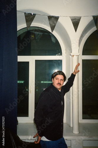 Eccentric man dancing in front of white windows at houseparty photo