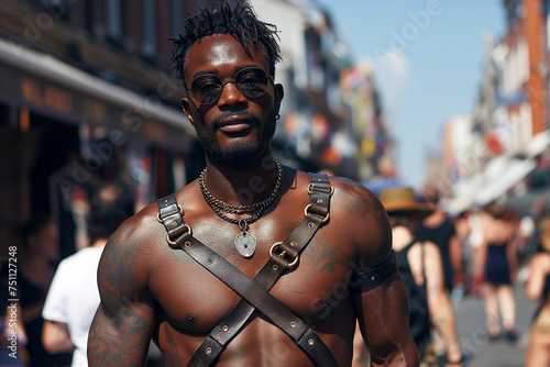 Brutal sexy muscular black gay man in leather harness at the LGBT parade on the street