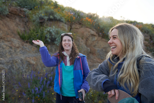 A blonde and brunette wave bugs away on a trail photo