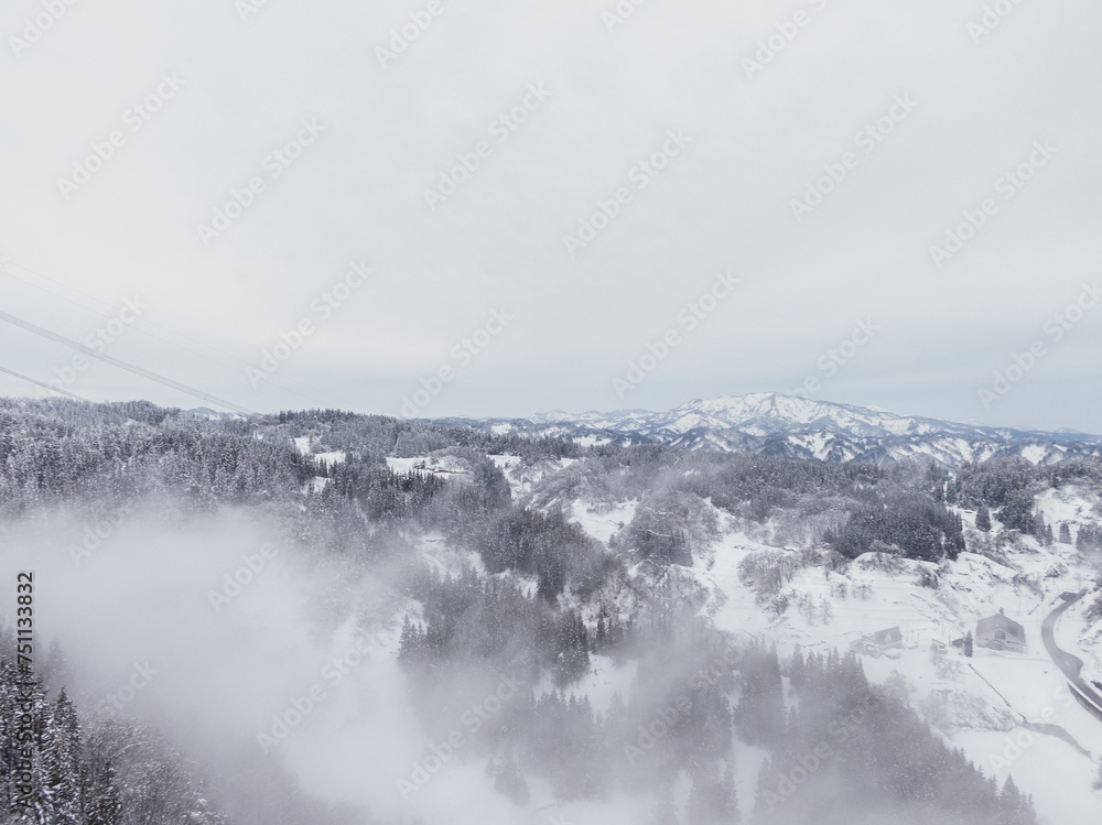 ドローン写真：霧が立ち込める、綺麗な雪に覆われた雪山