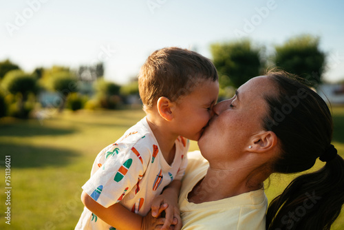 Happy mother and son kissing each other in park in day photo
