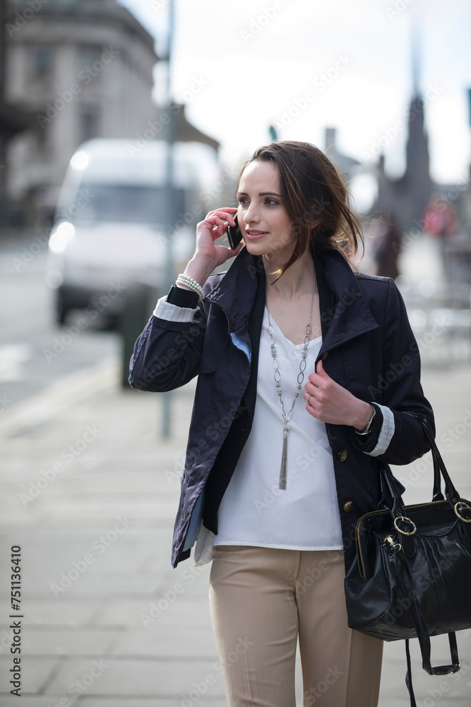 Modern Business woman, talking on mobile phone outside.