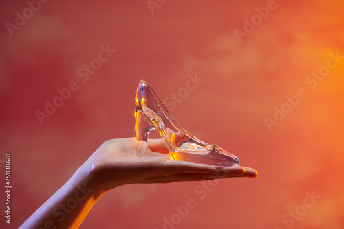 Small crystal slipper on a woman's hand on a hard light background photo