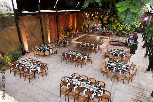 View of an empty venue with wooden tables for a wedding setup