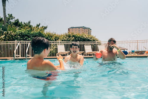 Father playing in the pool with his two teen sons.  photo