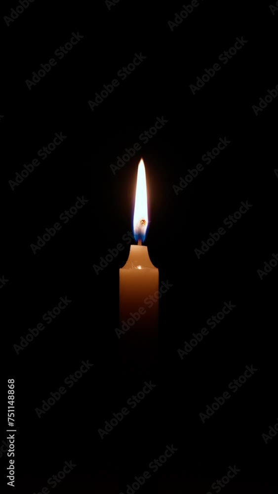 Vertical shot of a burning wax candle in the dark. The candle flame symbolizes memory, grief, loss. Religious ceremony concept. Vertical shot of a burning wax candle in the dark. The candle flame symbolizes memory, grief, loss. Religious ceremony concept.