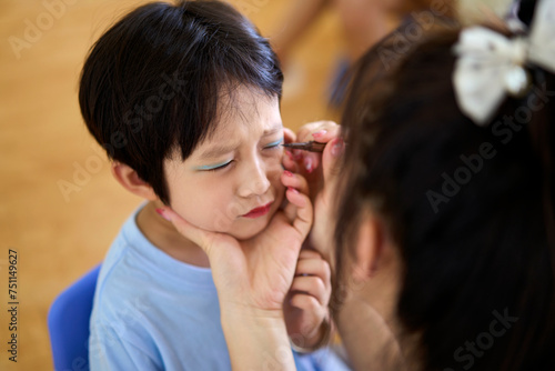 Little Asian boy, doing makeup for the performance on stage photo