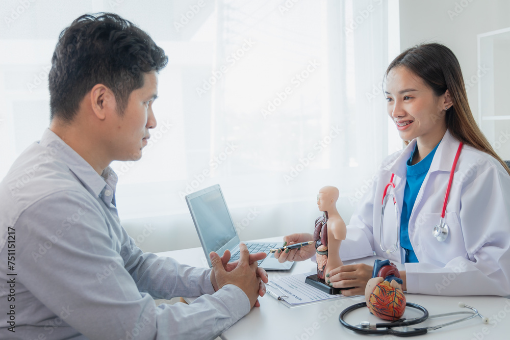 Heart disease. Female doctor gives advice on heart disease treatment. A cardiologist while giving a consultation shows an anatomical model of a human heart to an elderly patient talking about heart di Heart disease. Female doctor gives advice on heart disease treatment. A cardiologist while giving a consultation shows an anatomical model of a human heart to an elderly patient talking about heart di
