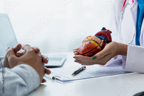 Heart disease. Female doctor gives advice on heart disease treatment. A cardiologist while giving a consultation shows an anatomical model of a human heart to an elderly patient talking about heart di