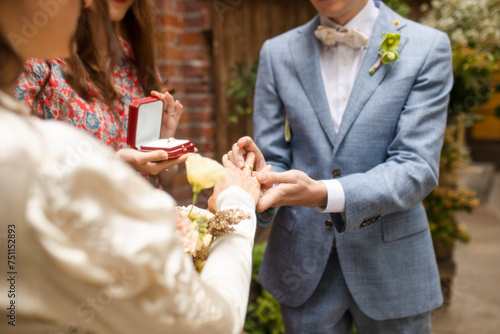 The groom puts a ring on the ring finger of the bride photo