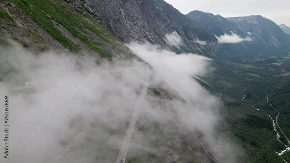 Aerial shot of a cloud covered hairpin bend in the Trollstigen in Norway as it snakes down the steep valley side. The road is covered with cloud and a Tour bus is approaching the sharp corner. Aerial shot of a cloud covered hairpin bend in the Trollstigen in Norway as it snakes down the steep valley side. The road is covered with cloud and a Tour bus is approaching the sharp corner.