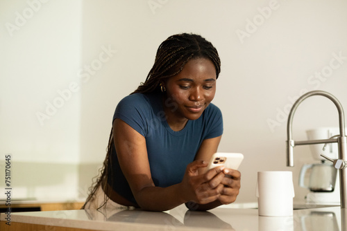 Woman Using Mobile Phone in Kitchen  photo