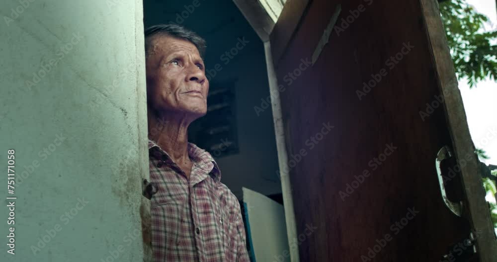 An Asian man who is an elderly worker, opened the door and looked up at the sky as if something had happened to the earth's atmosphere. Used in film concepts, humanity, documentaries and others. An Asian man who is an elderly worker, opened the door and looked up at the sky as if something had happened to the earth's atmosphere. Used in film concepts, humanity, documentaries and others.