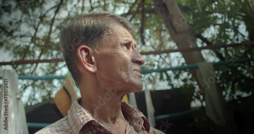 An Asian man who is an elderly worker, looked up at the sky in his house area as if something had happened to the earth's atmosphere. Used in film concepts, humanity, documentaries and others.