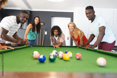 Diverse group of friends playing pool, focused on the game