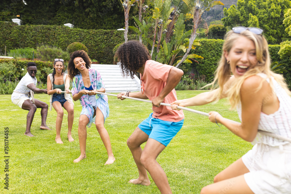 Fototapeta premium Diverse group of friends enjoy a tug-of-war game on a sunny day