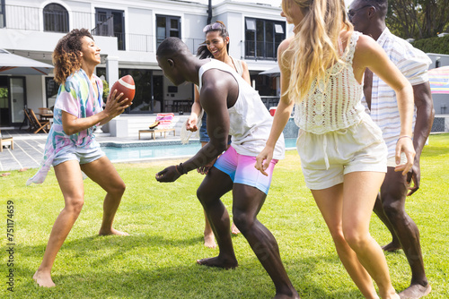 Diverse group of friends enjoy a playful game of football in a sunny backyard