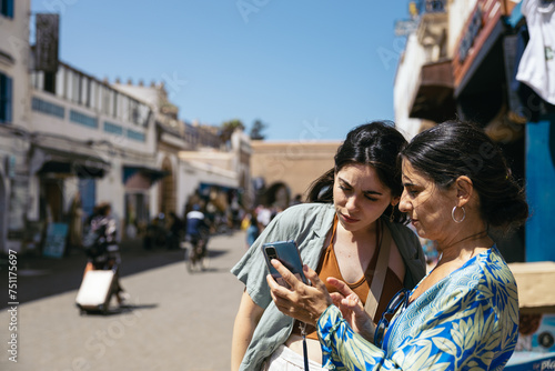Related women using smartphone outdoors photo