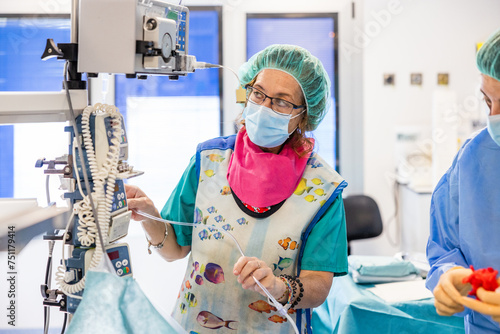 Woman doctor in uniform and cap standing near equipment photo