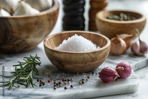 Sea salt in a wooden bowl with garlic and mixed peppercorns on a marble board. Close-up with selective focus. Gourmet cooking and seasoning concept. Design for culinary blog, recipe background