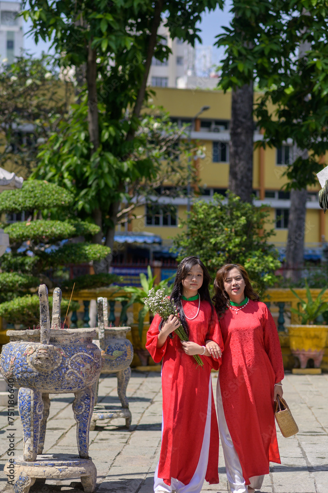 Portrait of Vietnamese mother and daughter in red Ao Dai Dress visit the pagoda on Tet holiday , Lunar new year