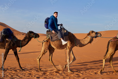 Joyful tourist explores the desert on a guided camel tour. photo