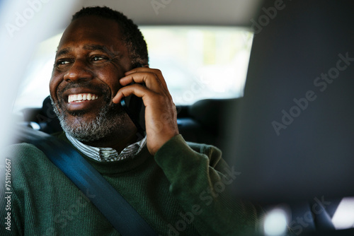 Cheerful middle age man talking on smartphone in car
