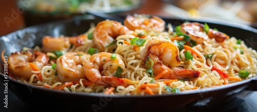 A skillet filled with sizzling shrimp and noodles, creating a flavorful and savory dish. The shrimp are juicy and succulent, while the noodles are coated in a delicious sauce.