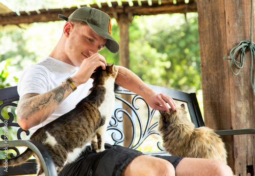 Young man befriending cats in a cat sanctuary. photo