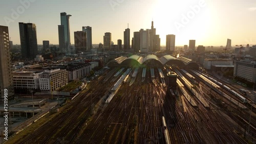 AERIAL: Frontal flight over Frankfurt am Main early morning in yellow-brown range. Central train station Germany, train tracks with low traffic. High angle view of the station building. photo