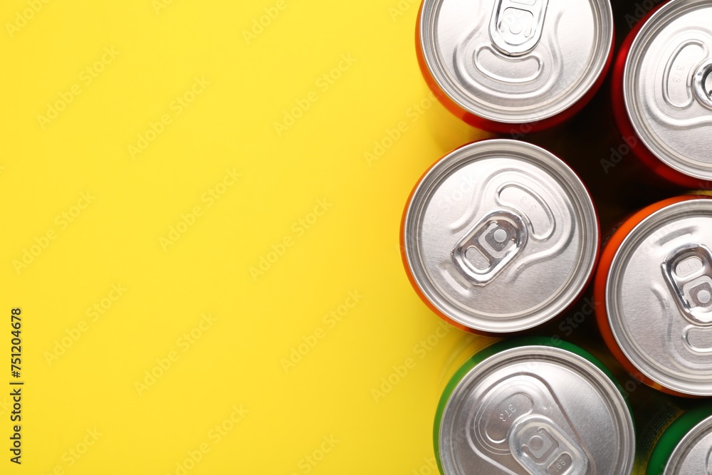 Energy drink in cans on yellow background, top view. Space for text Energy drink in cans on yellow background, top view. Space for text