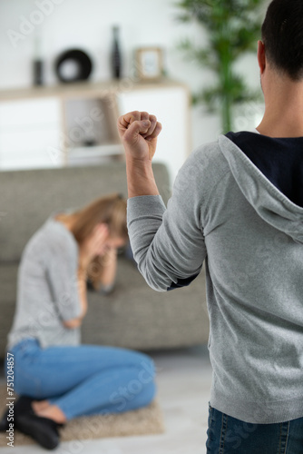 man raising his fist to cowering woman photo