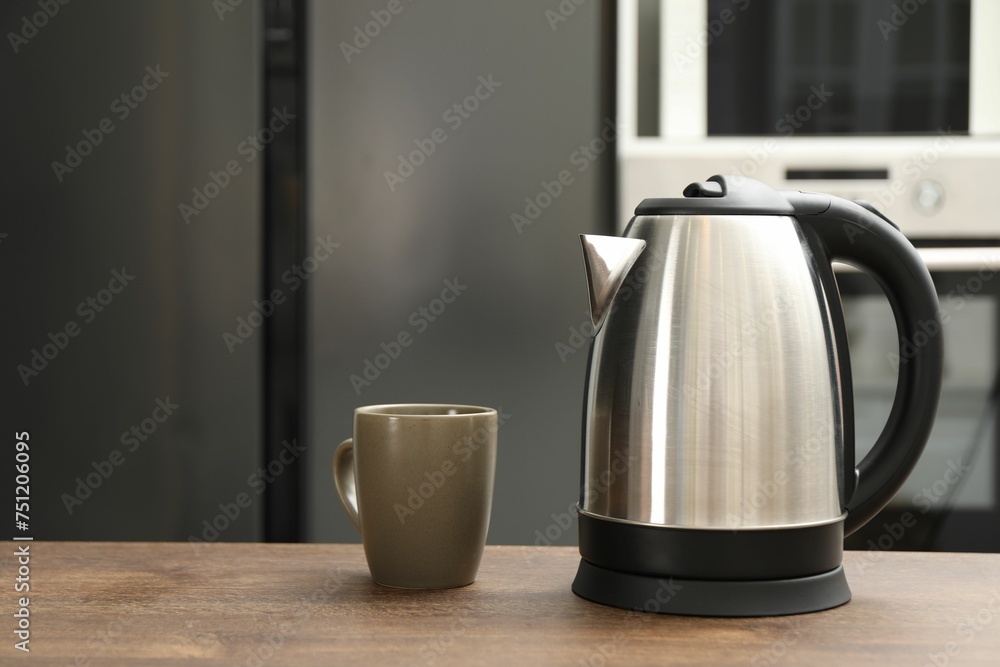 Modern electric kettle and cup on table in kitchen. Space for text Modern electric kettle and cup on table in kitchen. Space for text