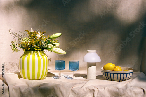 Stylish summer still life from a vase with flowers and blue glasses 