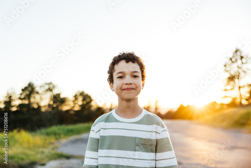 Portrait of cute curly haired boy outside.
